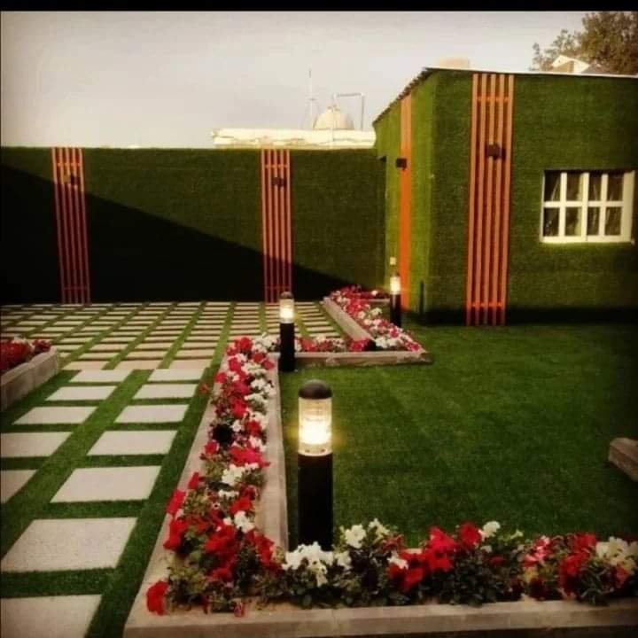 "صورة حديقة تحتوي على ثيل صناعي مع ورود ملونة وأحواض زراعية مرتّبة."