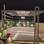 "مظلة مع جلسة كنفات مريحة وأحواض زرع مرتبة لتنسيق حدائق أنيقة."