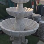 شلال صناعي مع نافورة مائية وحديقة مزينة بأحواض زهور وجلسة خارجية حديثة وعصرية.