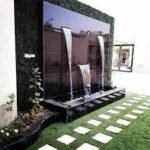 شلال صناعي مع نافورة مائية وحديقة مزينة بأحواض زهور وجلسة خارجية بتصميم عصري وجميل.