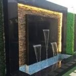 شلال صناعي مع نافورة مائية وحديقة مزينة بأحواض زهور وجلسة خارجية حديثة.